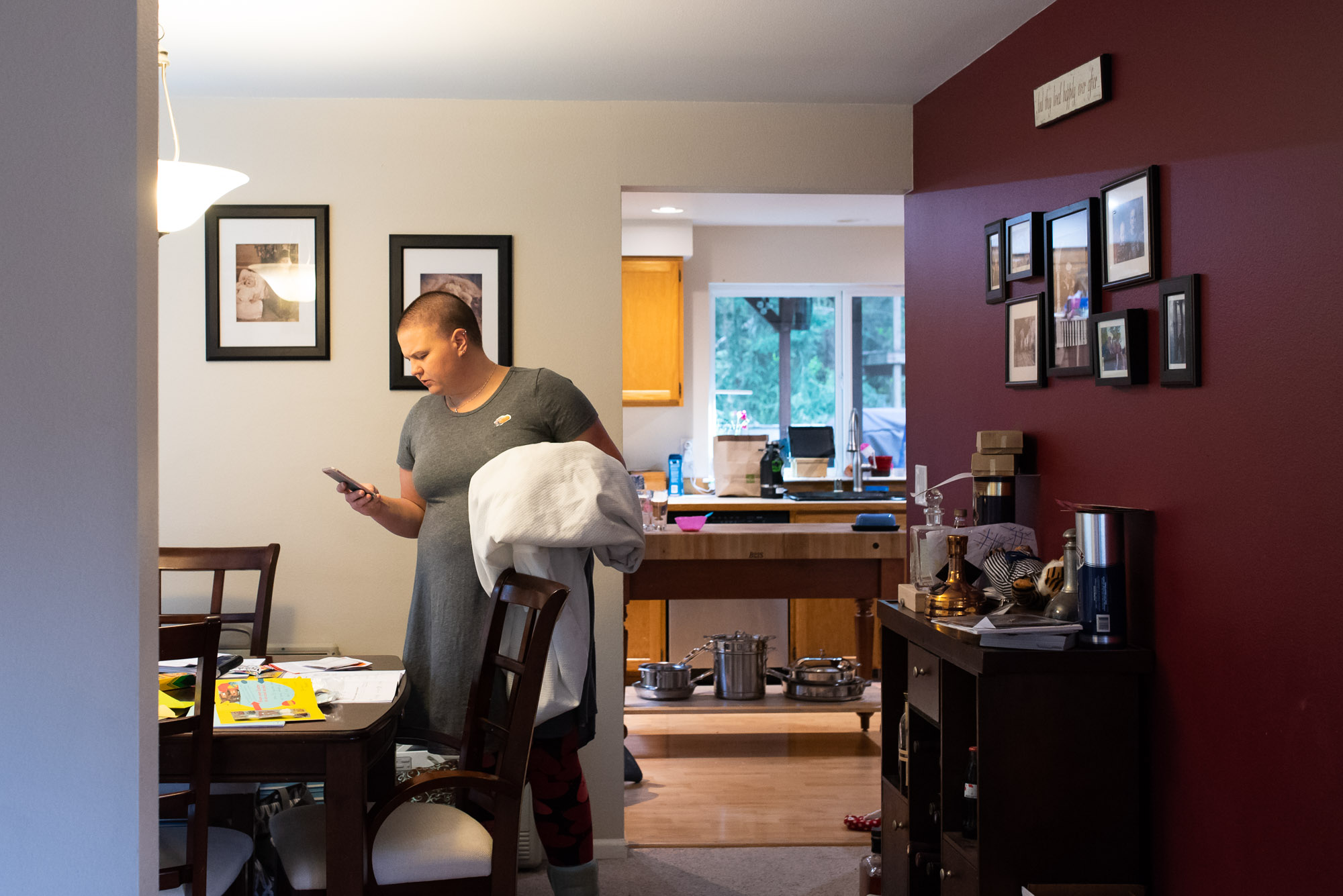 mother checks phone while holding laundry - documentary photography of military families