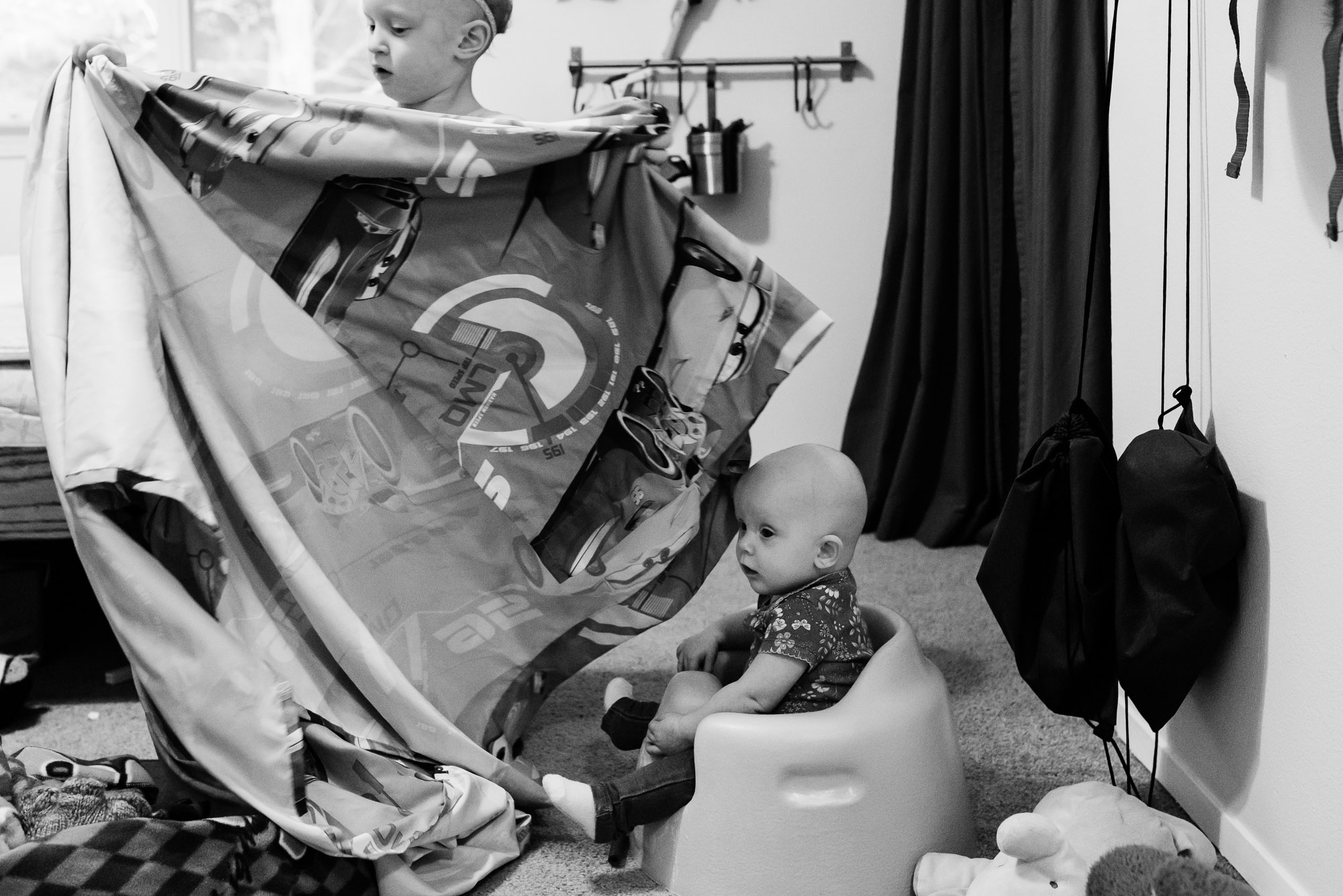 baby in booster chair next to sister extending blanket - documentary photography of military families