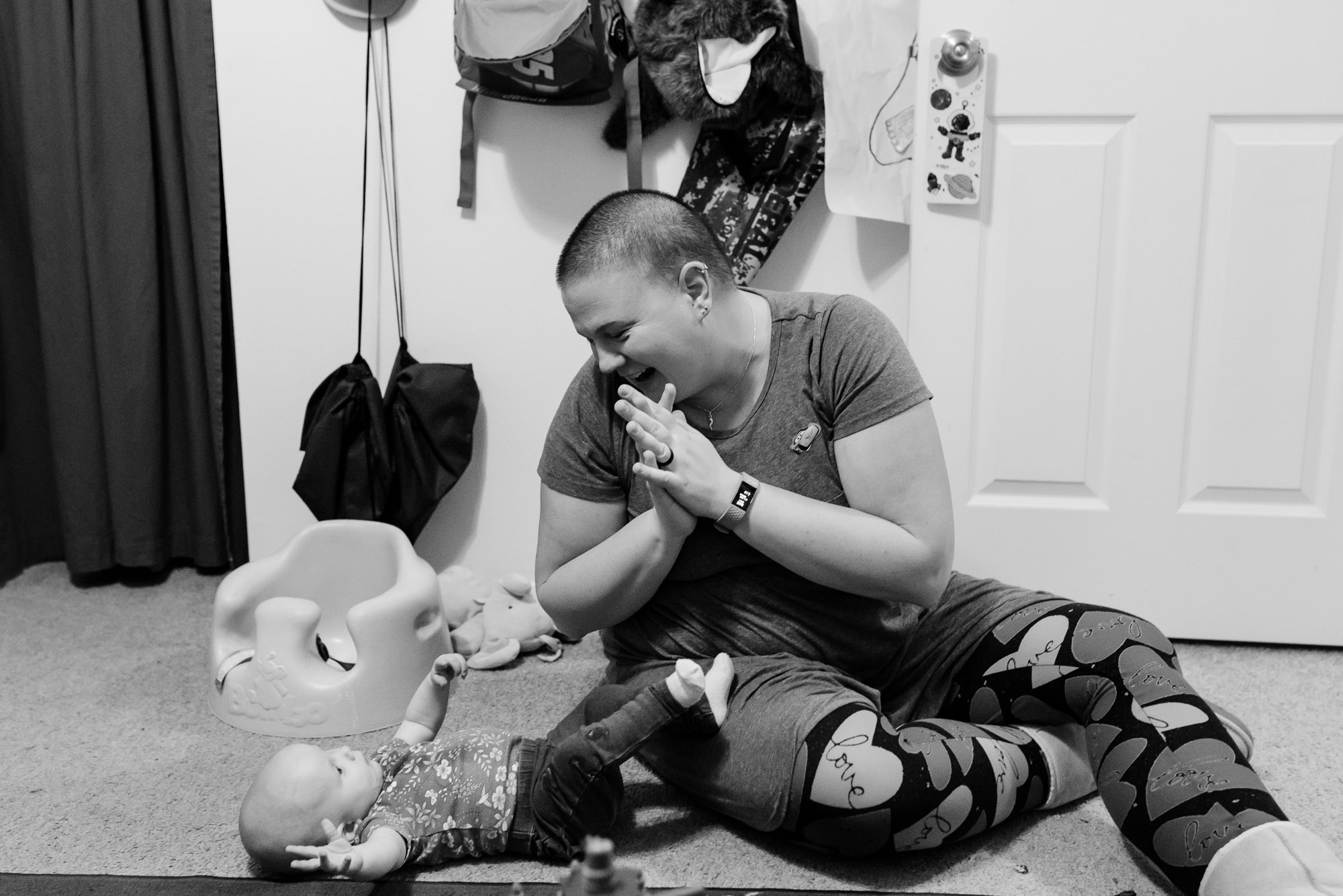 mother claps and celebrates baby rolling over - documentary photography of military families