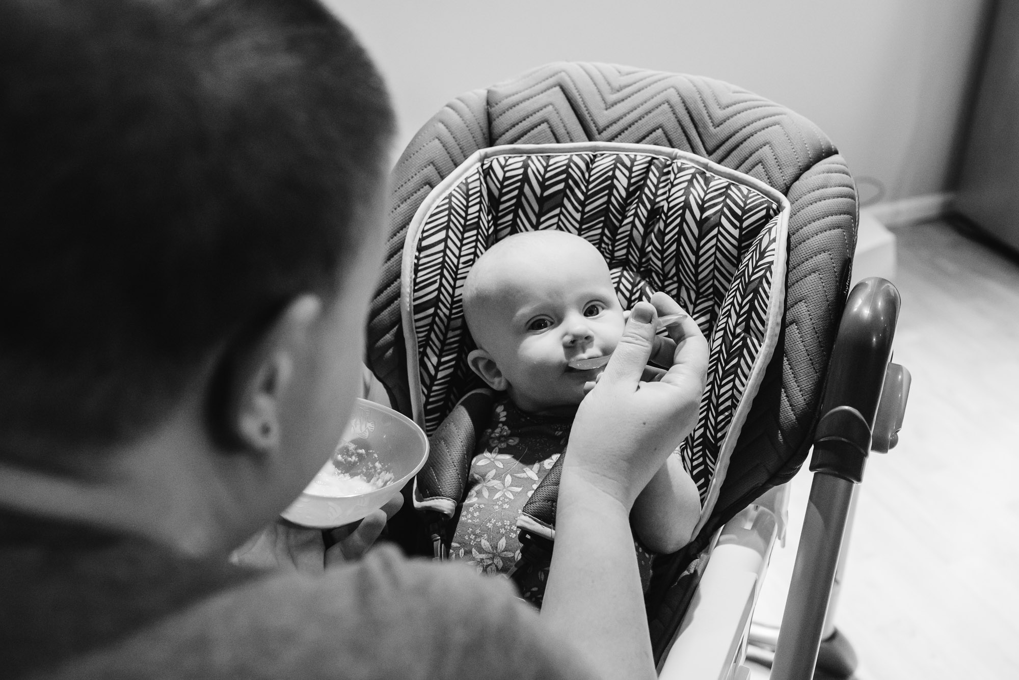 mother feeds baby rice cereal - documentary photography of military families