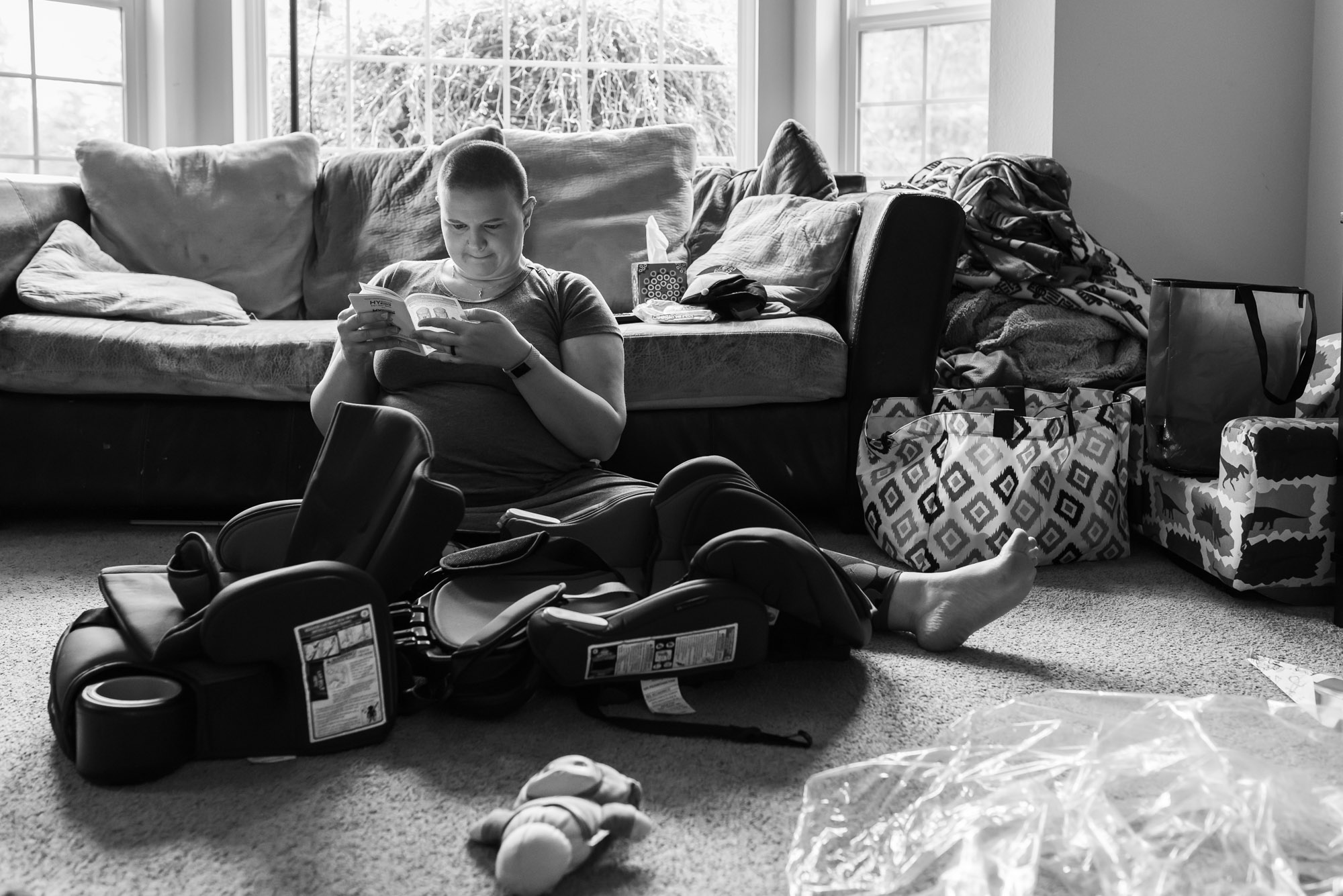 mother reads manual while assembling car seat - documentary photography of military families
