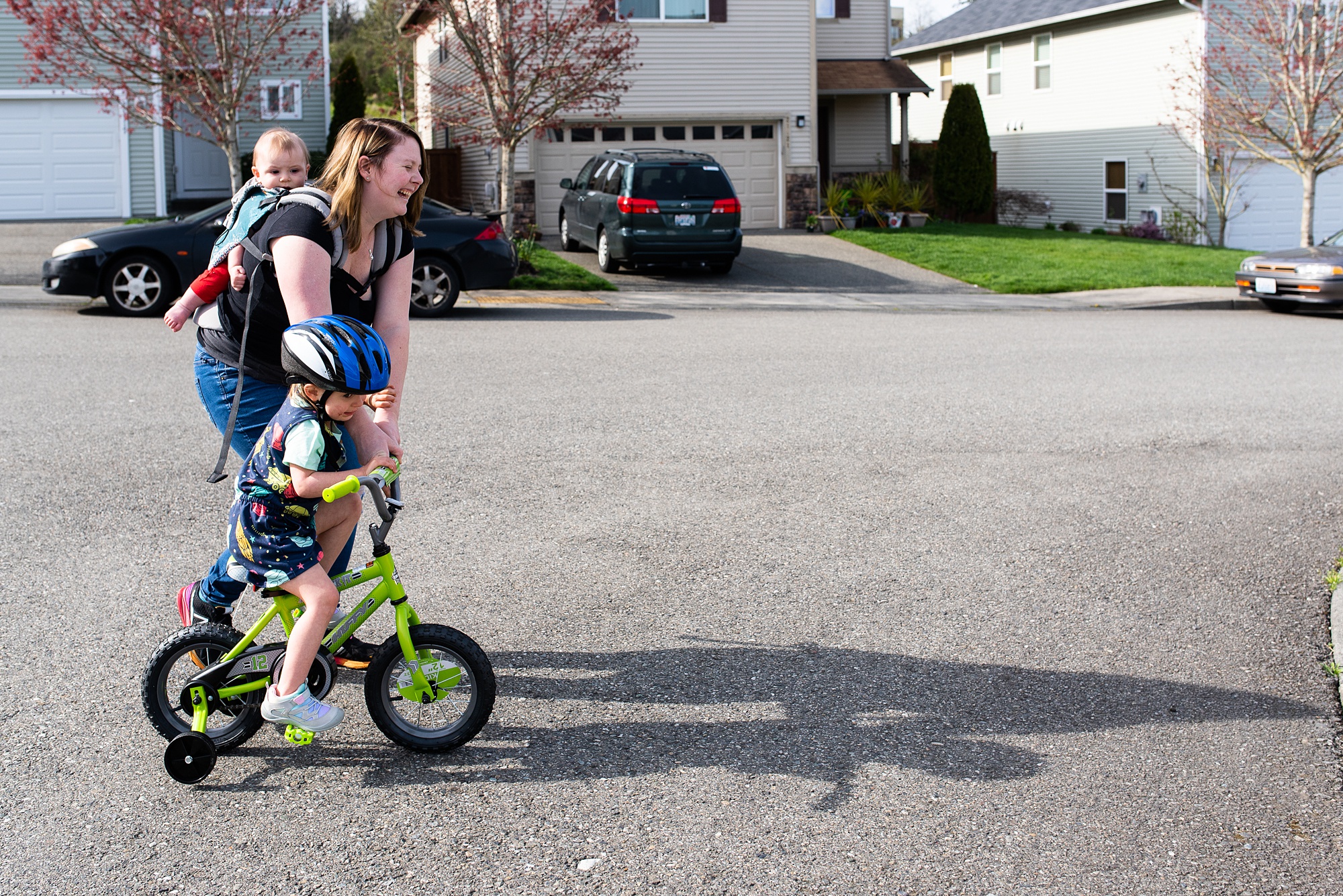 mom assists girl with bike while babywearing