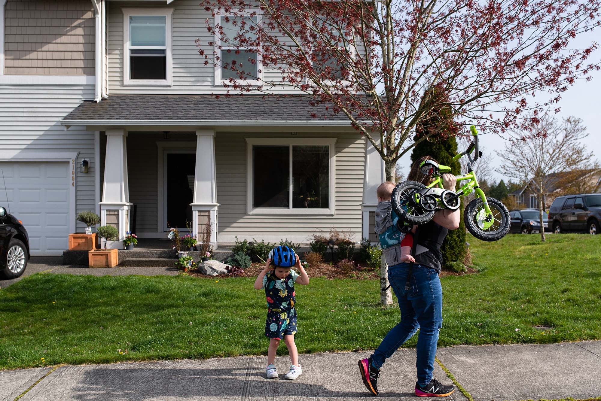 mom carries child bike home while wearing baby