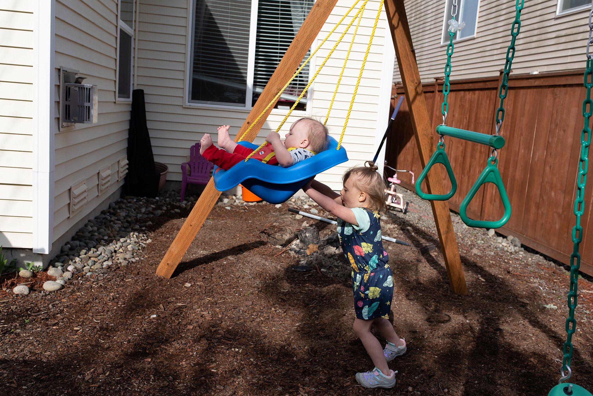 sister pushes little brother in swing