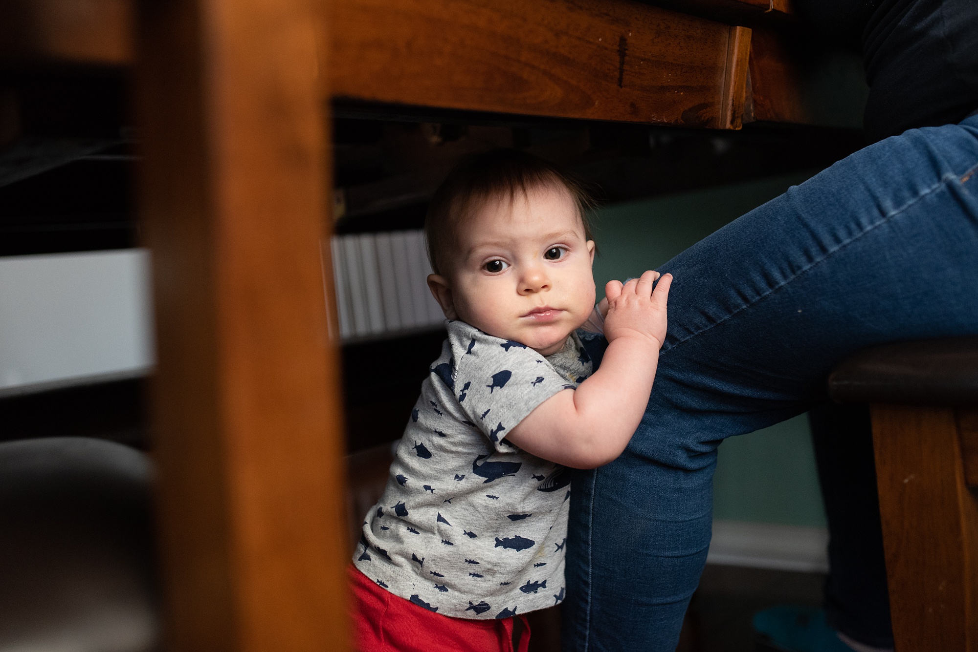 baby waits clings to mom's leg