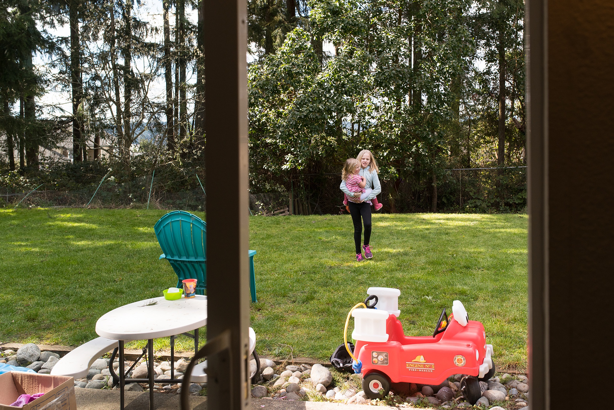older sister carries younger sister back into house - military family photography