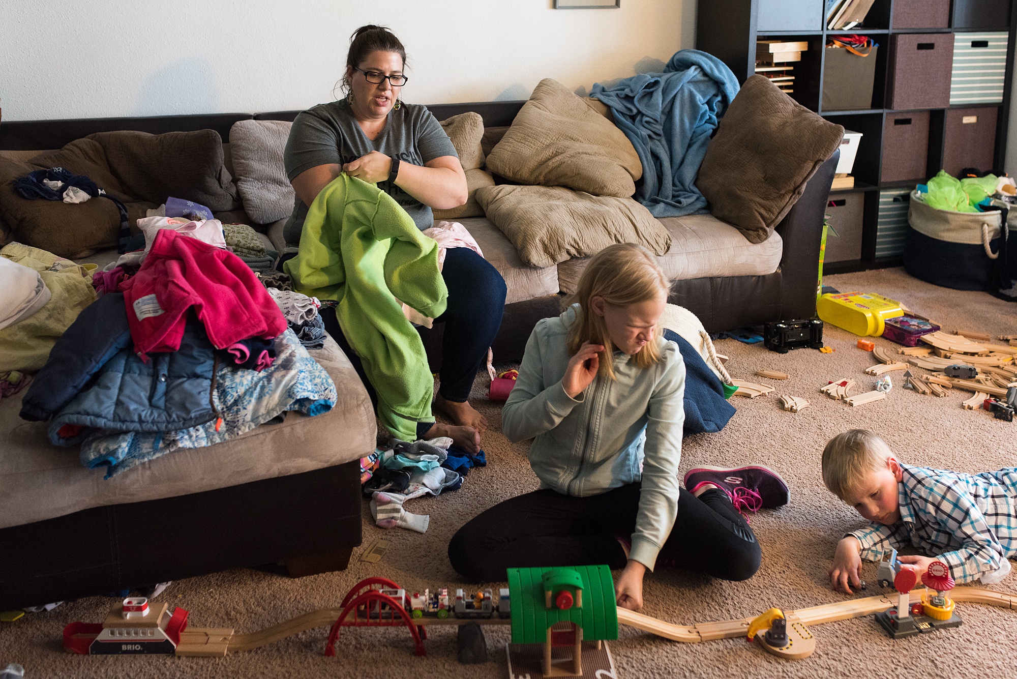 mom folds laundry while kids play on floor - military family photography