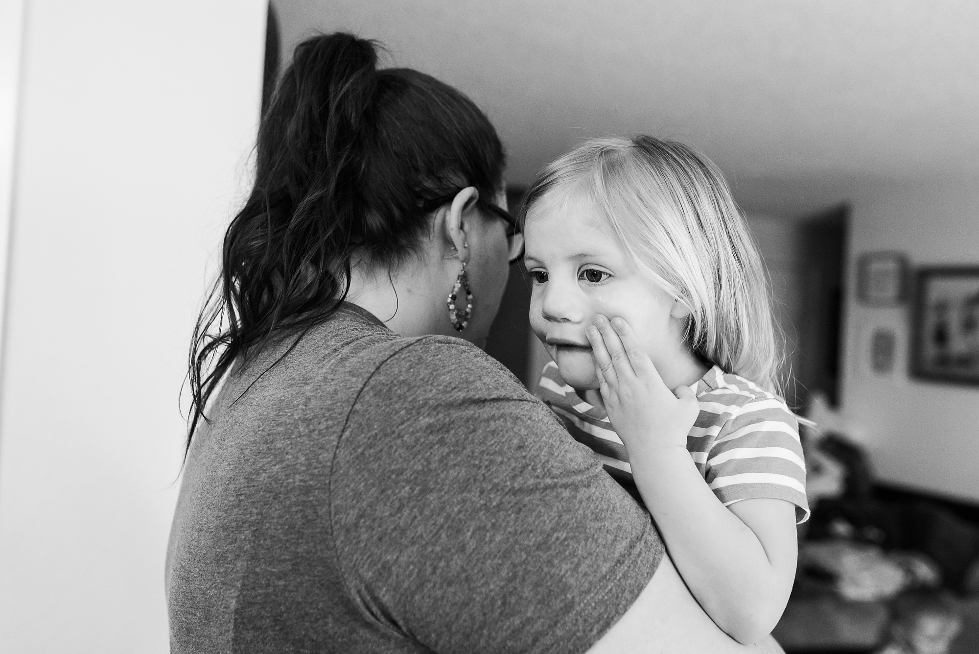 girl wipes away tear while mom holds her - military family photography