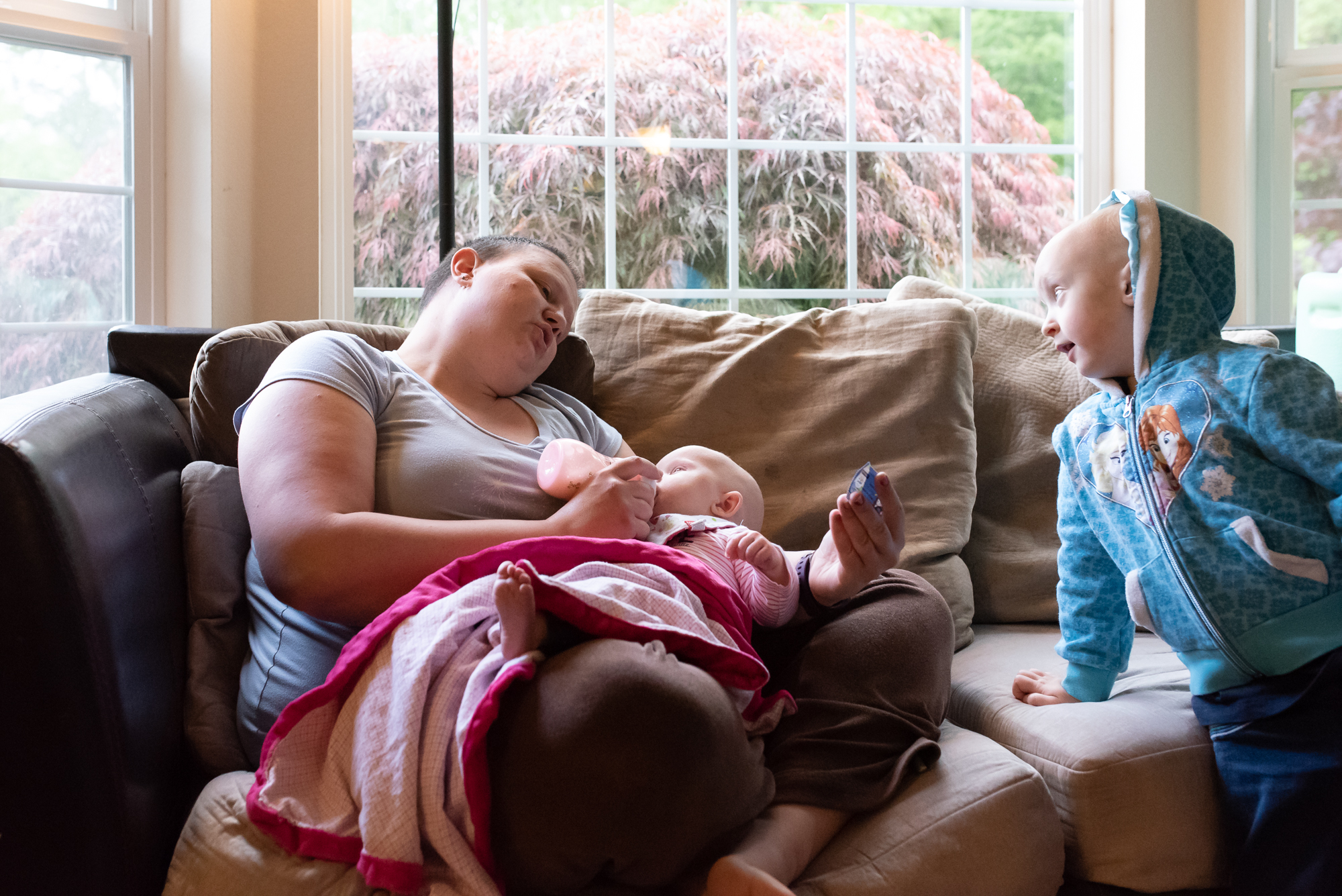 mom reclines and feeds baby while talking to older daughter