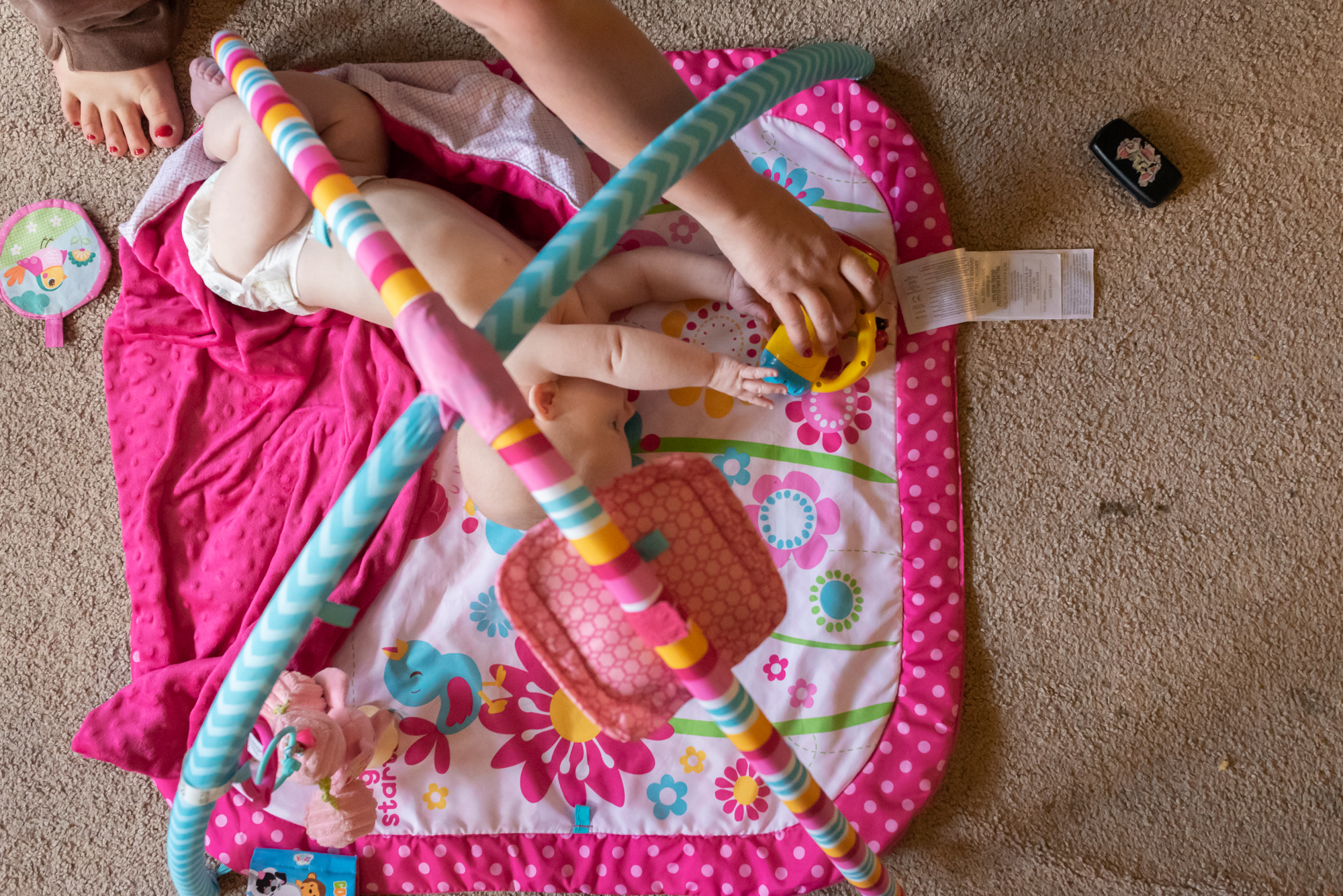 mom helps baby reach for toy